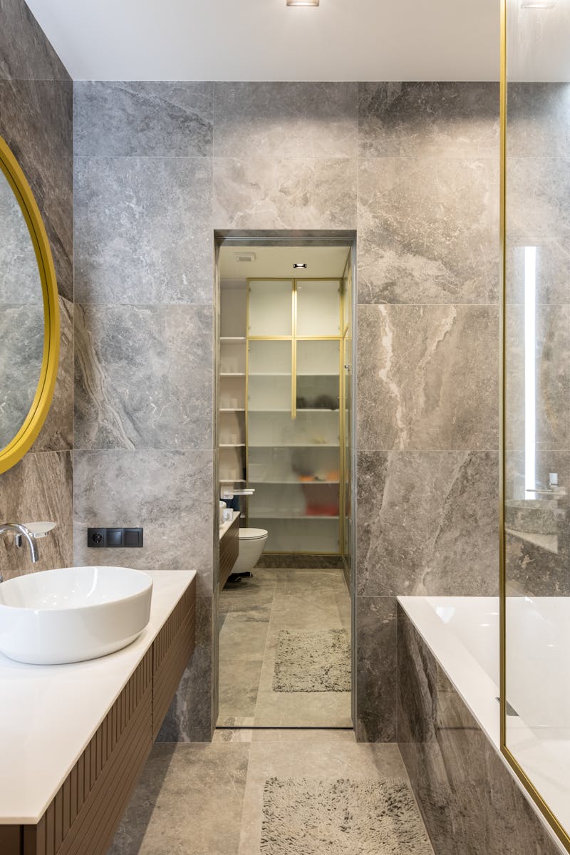 Elegant modern bathroom featuring marble walls, gold accents, and sleek fixtures for a luxurious feel.